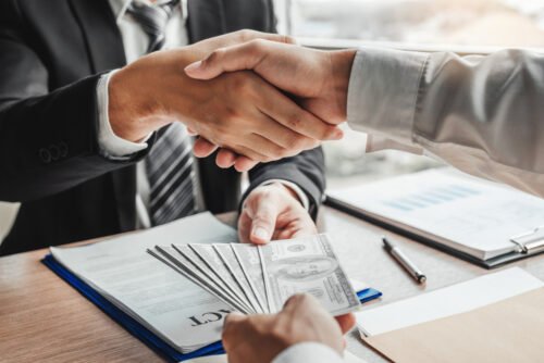 businessmen shaking hands getting paid